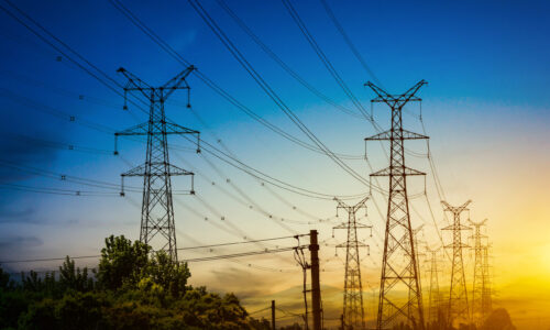 Sun setting behind the silhouette of electricity pylons